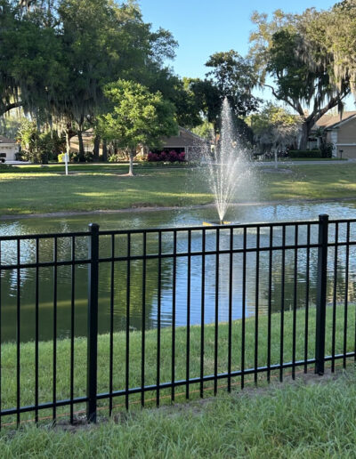 Aluminum fencing installed in the backyard, creating a secure and stylish barrier between the property and a scenic pond.