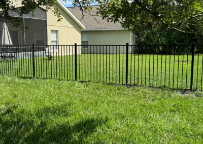 Black aluminum fencing installed along the side of a residential property, providing a sleek and durable boundary between neighboring yards.