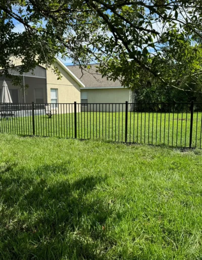 Black aluminum fencing installed along the side of a residential property, providing a sleek and durable boundary between neighboring yards.