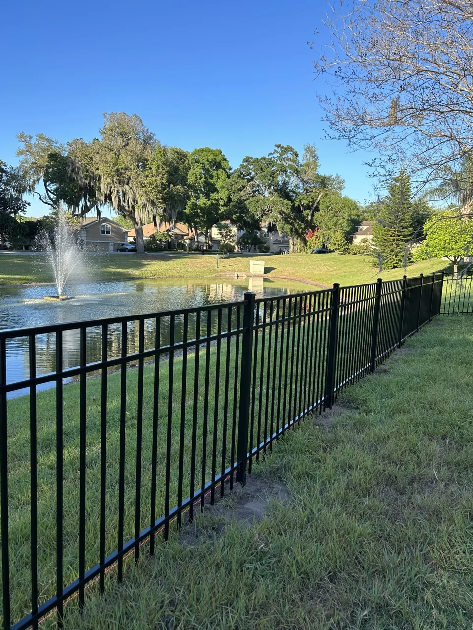 Aluminum fence installed by Primo Fence along pond with fountain.