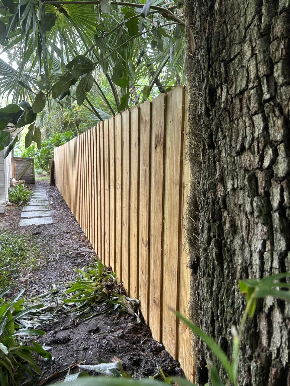 Wood privacy fence installed by Primo Fence along tree-lined backyard.