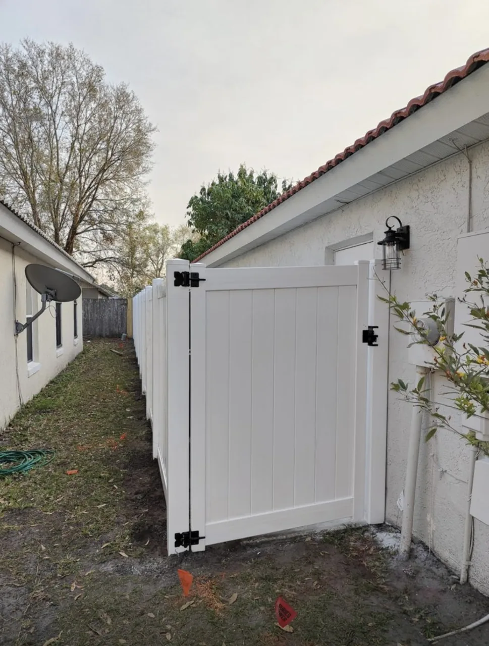 White vinyl fence and gate installed by Primo Fence alongside a residential home.